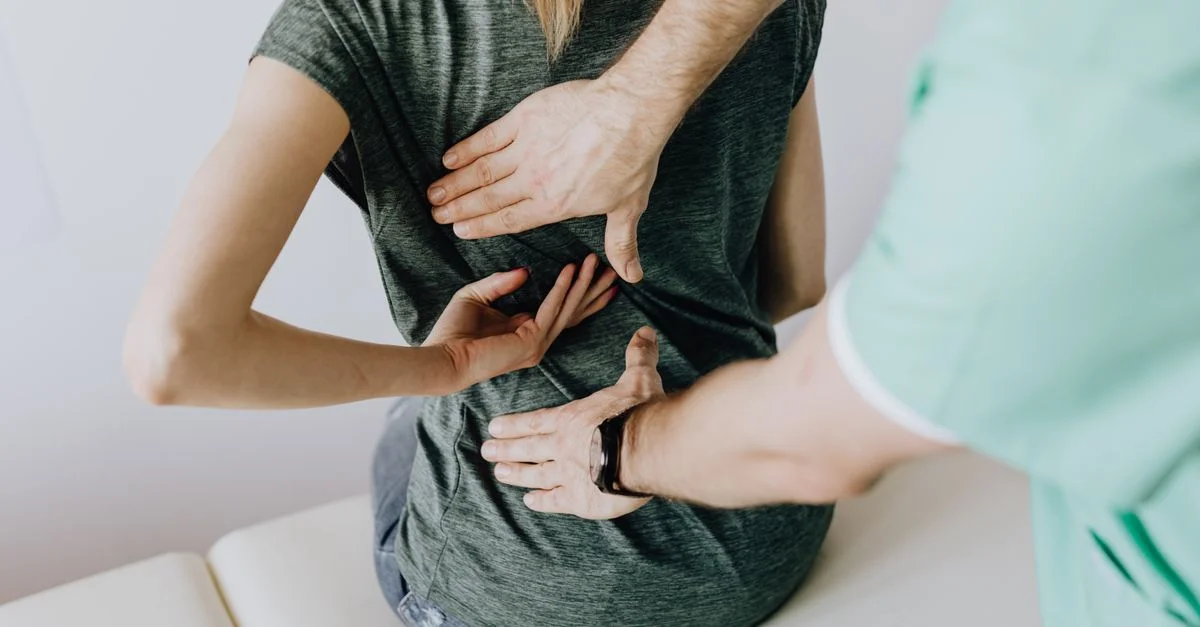 Un quiropráctico examinando la espalda de una paciente para aliviar el dolor y la incomodidad.