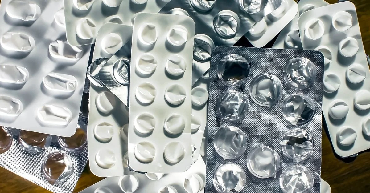 Acercamiento de varios paquetes de burbujas vacíos para medicamentos sobre una superficie de madera.