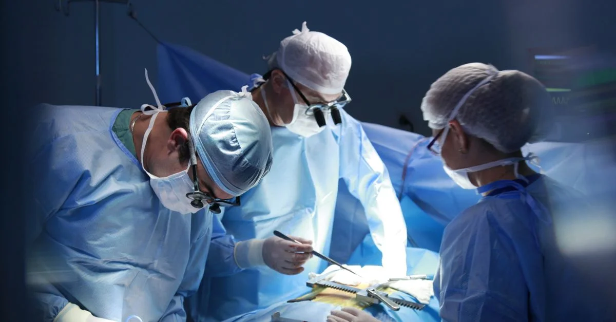 Equipo de cirujanos realizando una cirugía meticulosamente en una sala de operaciones estéril, destacando la atención médica experta.