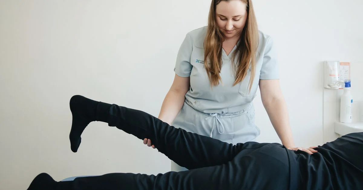 Un fisioterapeuta ayuda a un paciente a estirar la pierna durante una sesión de terapia en la clínica de Vilnius.