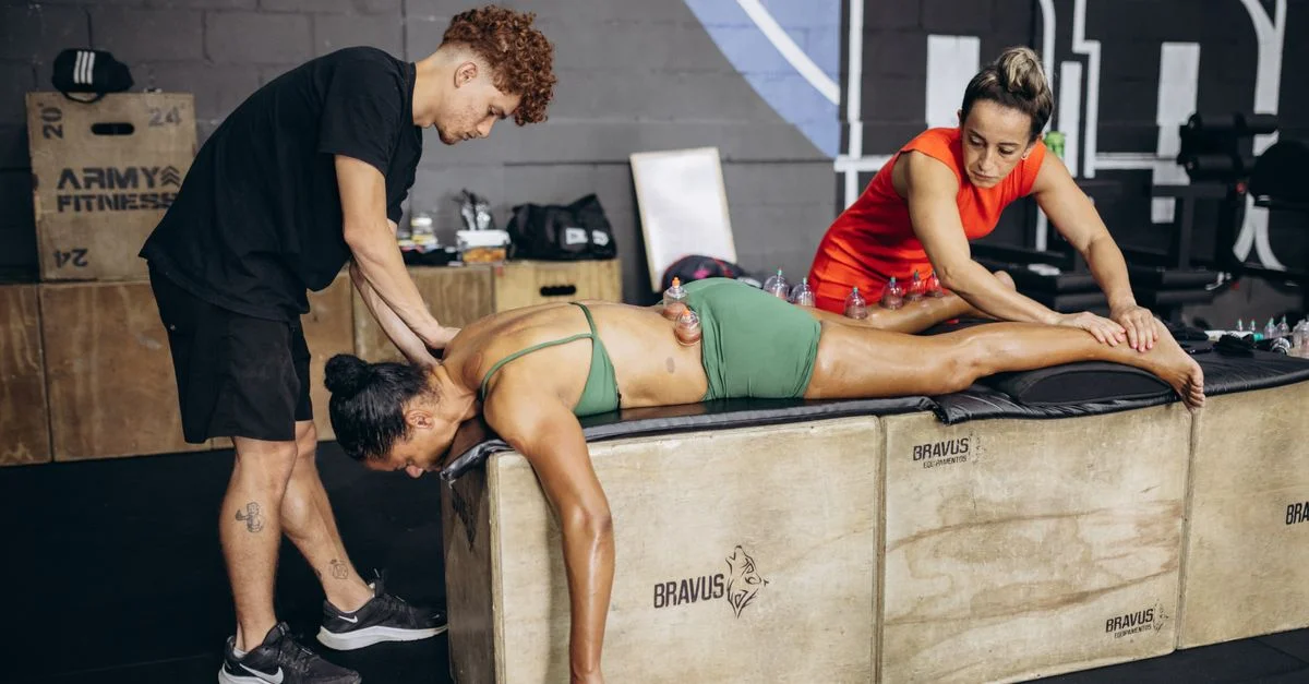 La atleta recibe terapia de ventosas para la recuperación muscular en un gimnasio con dos terapeutas.