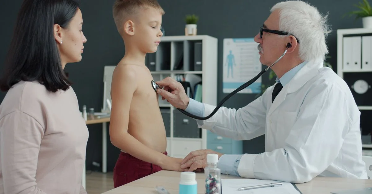 Un médico utiliza un estetoscopio para examinar a un niño pequeño en presencia de su madre en un consultorio médico.