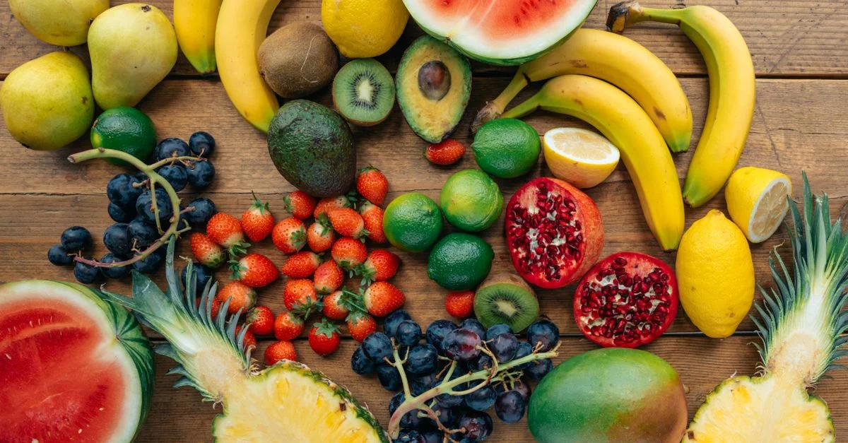Una exhibición vibrante de frutas frescas, incluyendo sandía, plátanos, uvas y más sobre una superficie de madera.