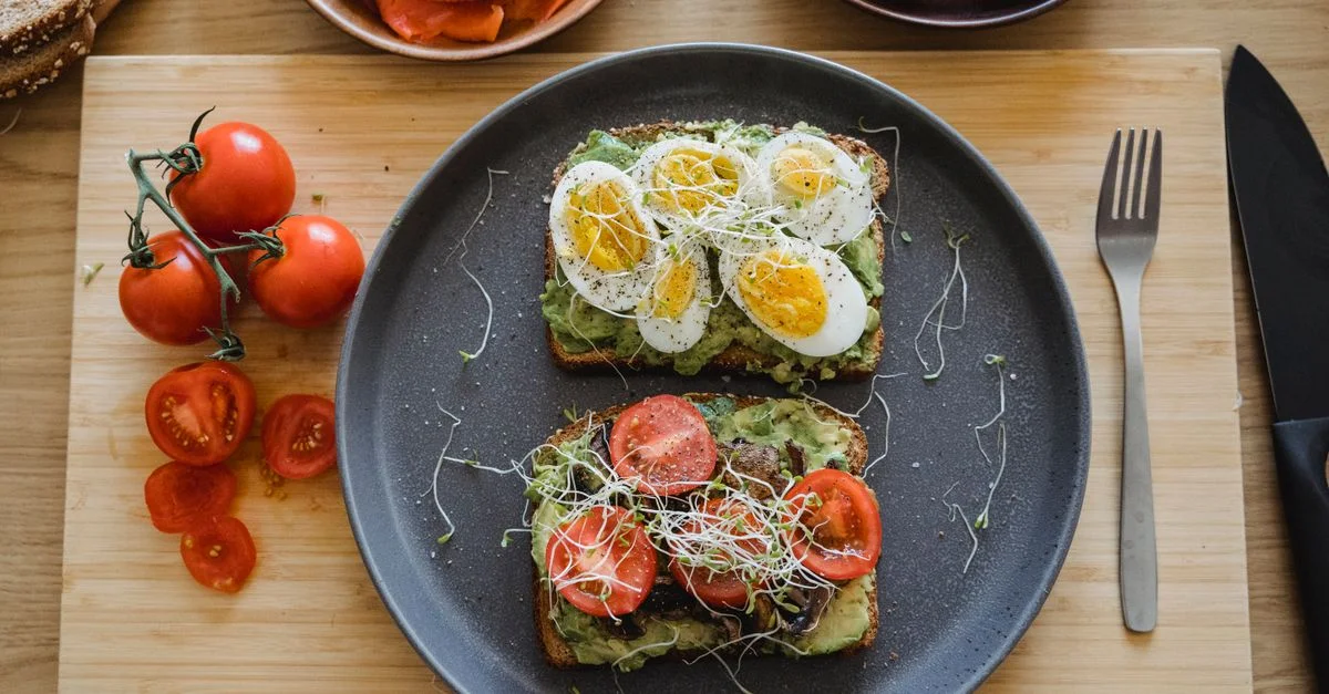 Deliciosa tostada de aguacate cubierta con huevos frescos y tomates, perfecta para un desayuno o almuerzo saludable.